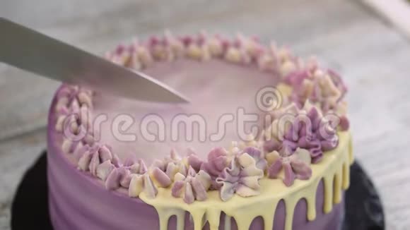 女人手在木头背景上用紫色奶油切蛋糕紫色蛋糕顶部视图视频的预览图