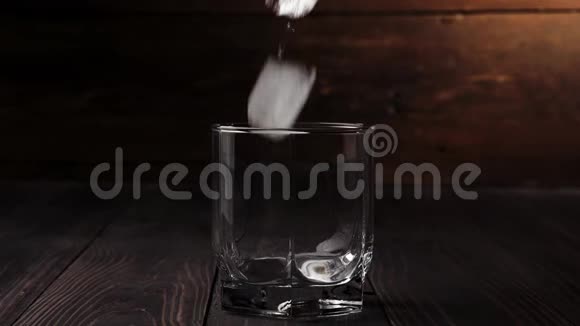 豪华威士忌冰落在一杯威士忌中位于木制桌子上背景是木制的不倒翁威士忌波旁酒视频的预览图
