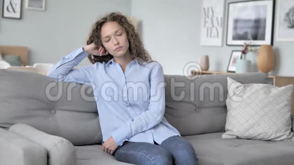 疲惫的卷发女人坐在沙发上睡觉视频的预览图
