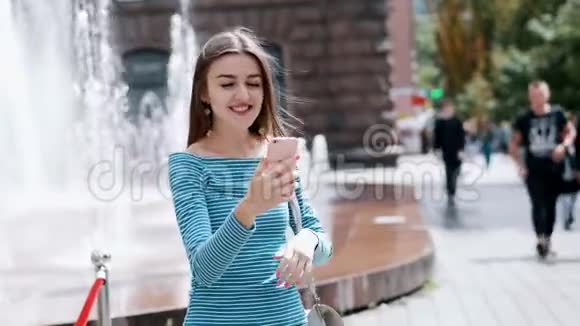 美丽的幸福女人在街上用手机和朋友通过视频通话视频的预览图