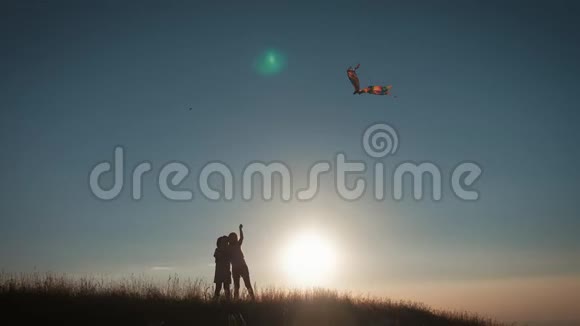 日落时两个孩子在田野里放风筝视频的预览图