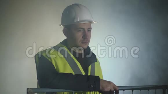 微笑的人穿着建筑工服和头盔站在黑色背景前聚光灯肖像视频的预览图