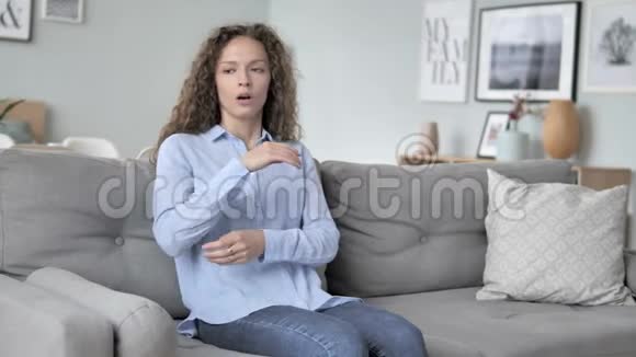 生病的卷发女人坐在沙发上咳嗽视频的预览图