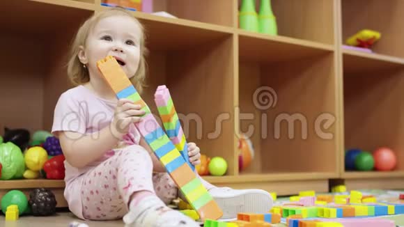 一个小女孩在幼儿园玩乐高积木拿起一个高塔的细节打破它并放置塔视频的预览图