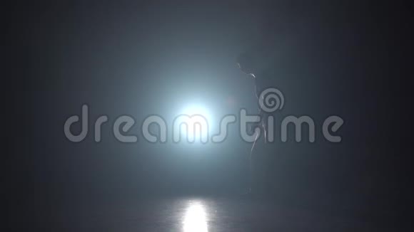 在黑暗中男性在灯光照射下缓慢移动剪影练习卡波伊拉视频的预览图
