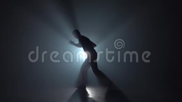 卡波伊拉黑暗中的男性剪影对着灯光聚光灯慢动作视频的预览图