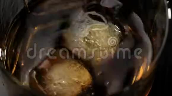 豪华威士忌冰块落在一杯威士忌中溅在黑色桌子上背景是木制的苏格兰威士忌视频的预览图