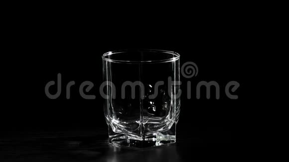 豪华威士忌手把金色的威士忌从一个方形的瓶子里倒入旋转的黑色桌子上的玻璃杯里不倒翁威士忌视频的预览图
