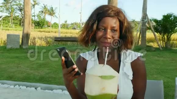 年轻快乐迷人的美国黑人女性在热带海滩度假胜地的手机上使用互联网社交媒体令人心寒视频的预览图