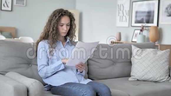 一位兴奋的卷发女子在阅读新合同时欢呼雀跃视频的预览图