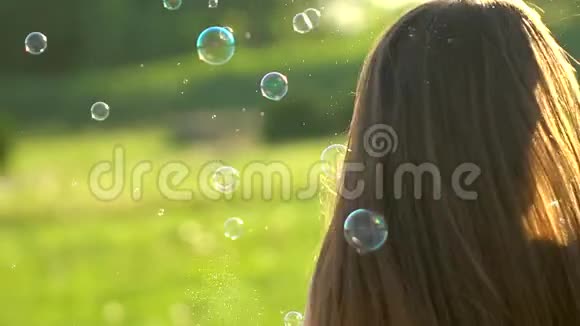 美丽的女孩长发在绿草公园的大自然中玩泡泡肥皂青少年户外快乐美丽的女人视频的预览图