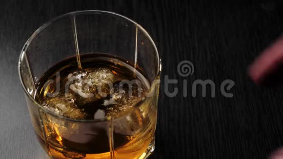 豪华威士忌手拿着一杯金色威士忌和真正的冷冰从黑桌上不倒翁威士忌视频的预览图