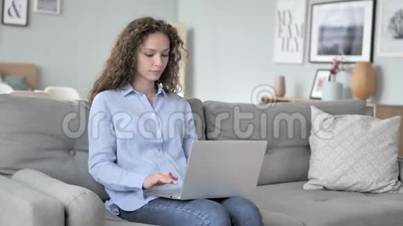 坐在创意工作场所的卷发女士在笔记本电脑上在线视频聊天视频的预览图