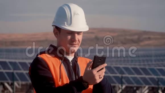 穿着橙色背心的工程师试图与工人联系以报告太阳能电池板运行中的缺陷视频的预览图