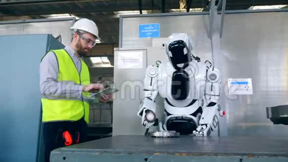 一个人在平板电脑上打字而一个半机器人在工厂工作视频的预览图