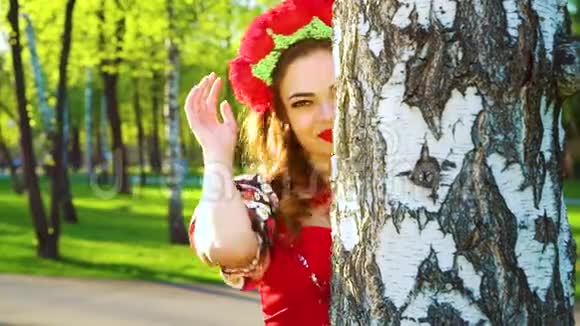 穿着民间风格服装的漂亮女人用镜头耀斑从桦树上窥视视频的预览图