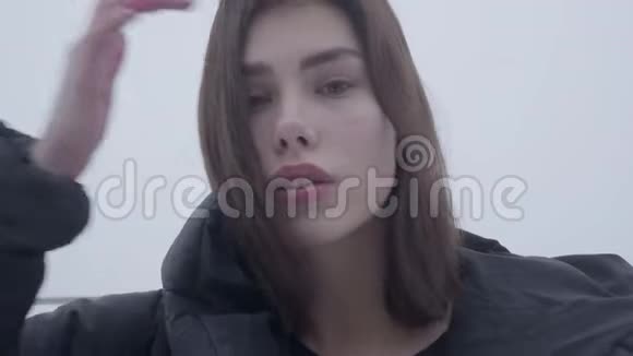 一个年轻漂亮的女孩的肖像黑发随风飘动站在一件黑色夹克衫里在雾蒙蒙的天气里视频的预览图