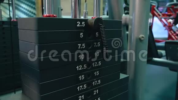 那个女孩在健身房把负载钉在机器上手的特写视频的预览图