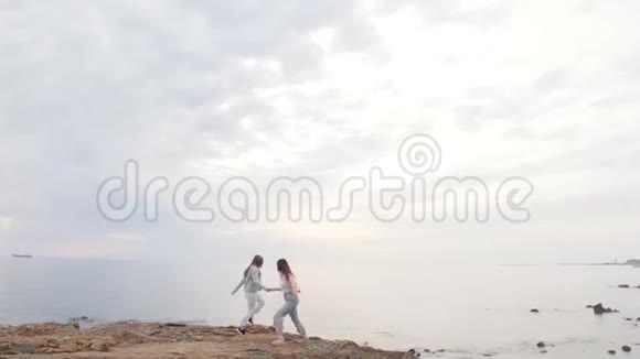 两个年轻快乐的女人在大海的背景下在山上跳舞视频的预览图