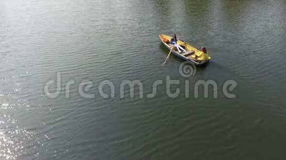 两个年轻漂亮的女孩在美丽的倒影湖或河流中间的小船上划船一个女人视频的预览图