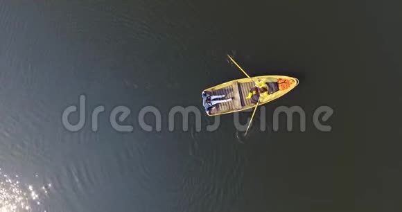 两个人在小船上划船穿过一个美丽的宽阔的反光湖或河积极的生活方式与视频的预览图