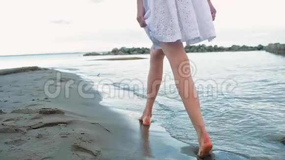 穿着短裙和黑色泳衣的女孩在海滩上走着模特的步态视频的预览图