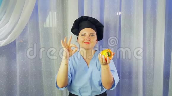 一个穿着围裙做饭的女人微笑着手里拿着一根黄色的胡椒用她的手表现得很好视频的预览图