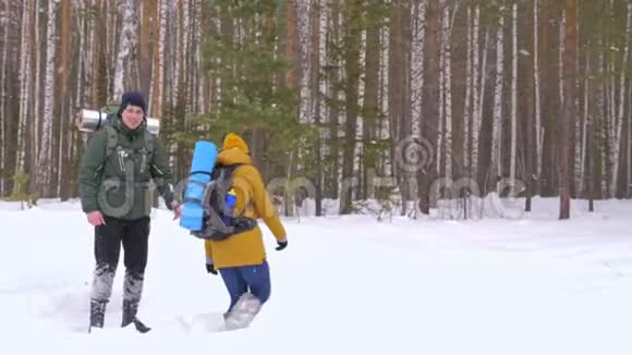 有趣的视频一个年轻人和一个女孩正沿着一条冬天的森林小径散步视频的预览图