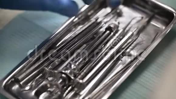 牙科医生正在从手术室的金属盒中选择和取出钢制无菌工具并进行手工特写视频的预览图