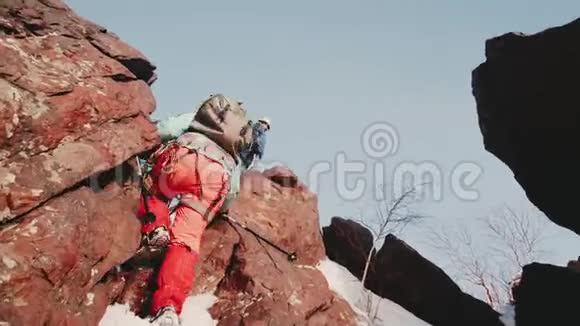 女孩爬上山缝来到站在山顶的人团队配备了背包视频的预览图
