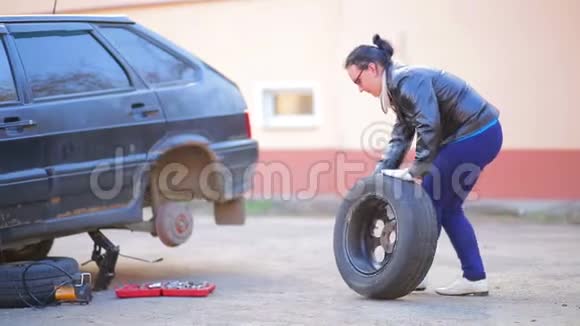 戴手套的女人把轮胎放在车轴上的圆盘上视频的预览图