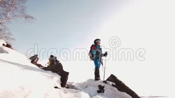 快乐的登山者站在白雪覆盖的山顶上手里拿着滑雪杆头上戴着护目镜视频的预览图
