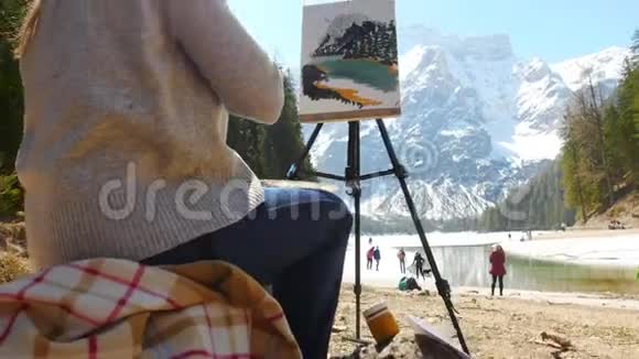 白云石一位年轻女子坐在河边用画架画一幅画视频的预览图