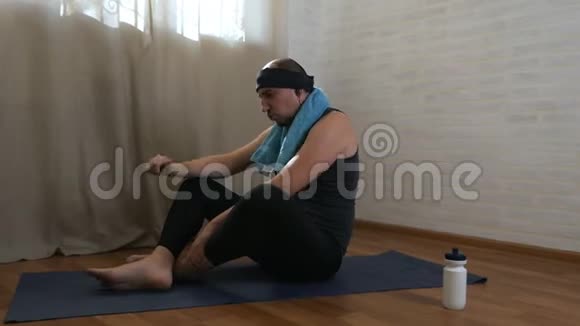 有趣的胖子正试图在背景上的垫子上做瑜伽练习男性瑜伽士视频的预览图