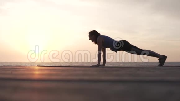 年轻女子站在海边的木桥上的高木板上视频的预览图