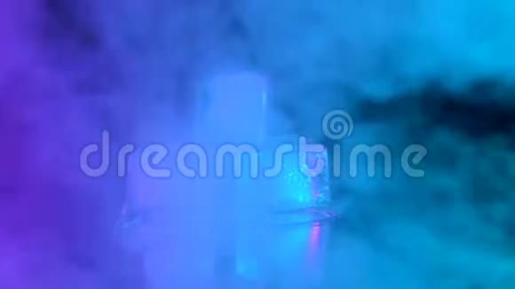 特写镜头三个冰块躺在有粉色和蓝色烟雾的镜子桌上视频的预览图