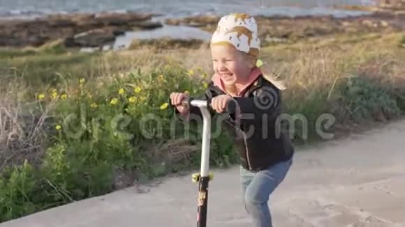 时髦的小女孩在海边的公园里骑摩托车视频的预览图