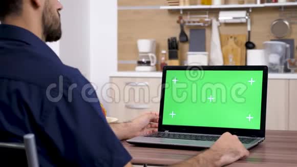 厨房里的男人用绿色屏幕模拟看电脑视频的预览图