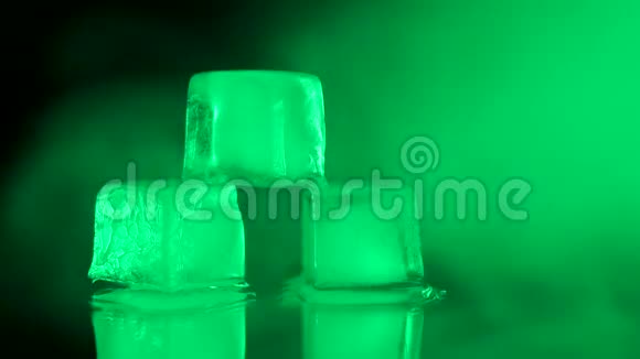 近景三个冰块躺在一张有绿色烟雾的镜子桌上视频的预览图