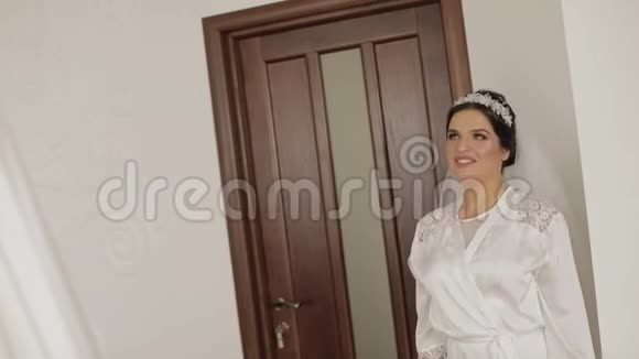 美丽可爱的新娘穿着睡衣戴着面纱奔向婚纱视频的预览图