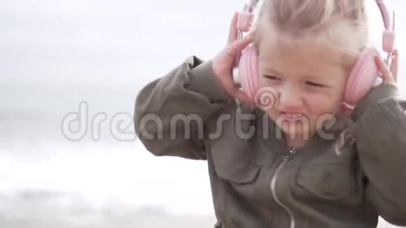 金发小女孩用耳机听音乐视频的预览图