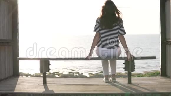 一个女人坐在海边的长凳上欣赏美丽的景色视频的预览图