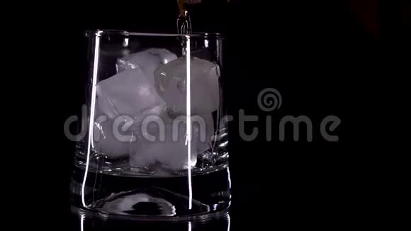 威士忌被倒入一个带有黑色背景的冰的玻璃杯中视频的预览图