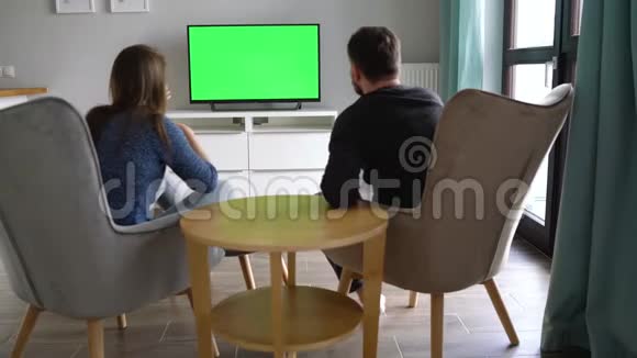 男人和女人坐在椅子上用绿色的屏幕看电视讨论他们看到了什么并用视频的预览图