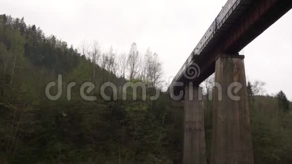 乘坐火车在一座古老的铁路桥上在一个山村的底部视频的预览图