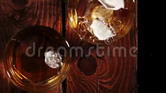 豪华威士忌冰块溅落成两杯棕色木桌上放着金色威士忌不倒翁威士忌视频的预览图