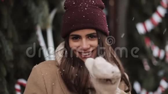 穿着冬装的年轻快乐美丽的女孩站在雪花中的画像微笑着朝视频的预览图