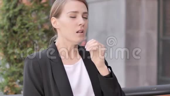 咳嗽病的年轻女商人坐在户外视频的预览图
