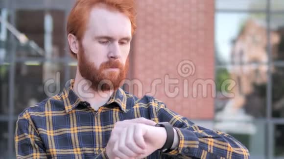 红胡子年轻人使用智能手表户外视频的预览图