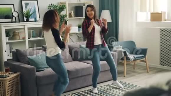 快乐的年轻女性在家里跳舞放松和听音乐而非裔美国女孩正在录制视频视频的预览图